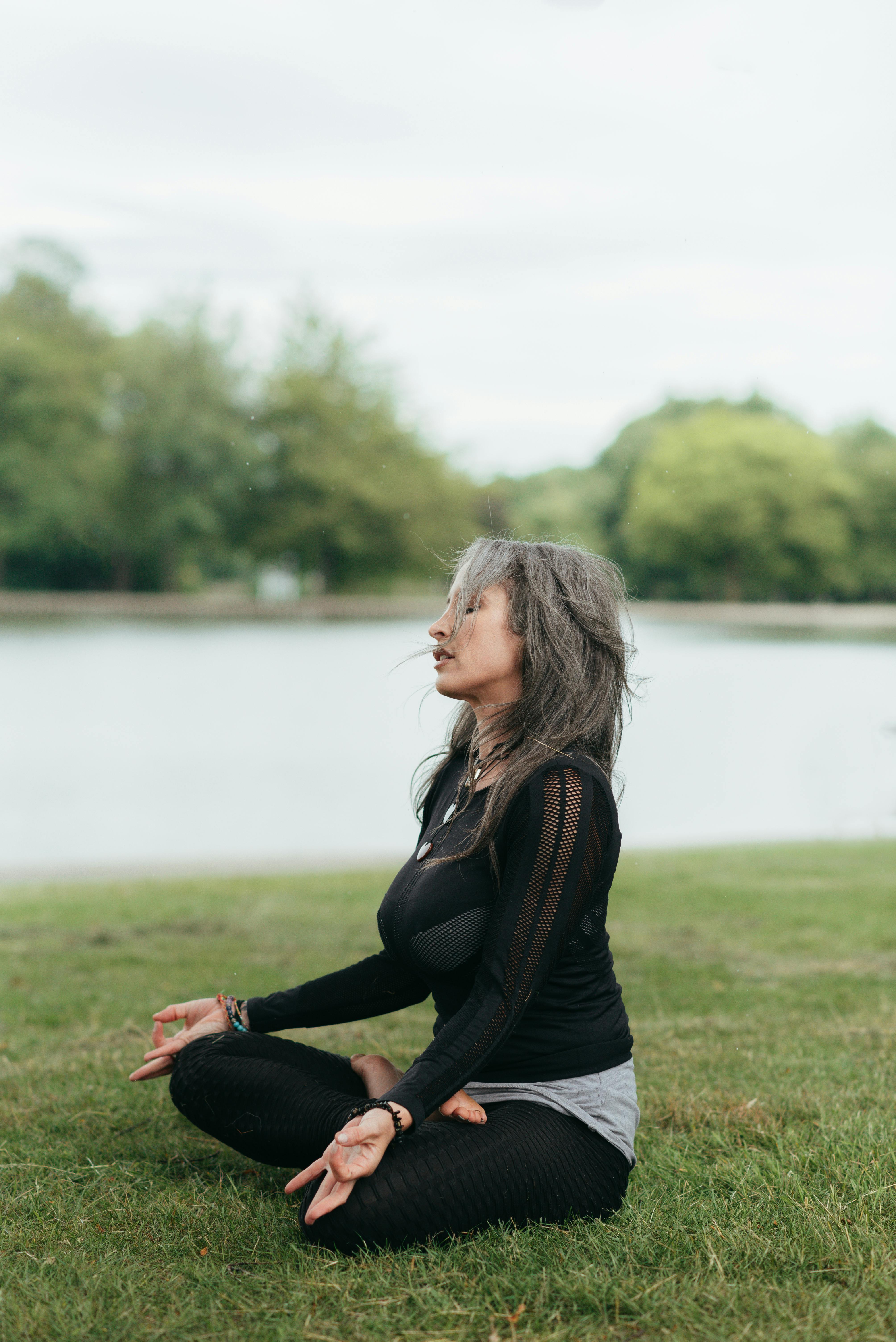 concentrated woman meditating in lotus pose on river shore