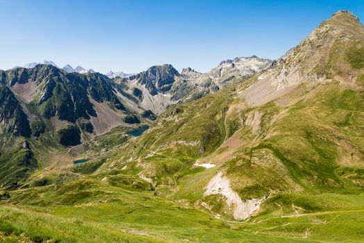 Majestic landscape of Pyrenees in summer, featuring lush valleys and rugged peaks under a clear blue sky.