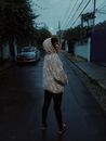 黄昏时分，一名身穿图案连帽衫的年轻女子站在圣保罗街头，散发着时尚而神秘的气息