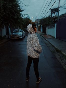 黄昏时分，一名身穿图案连帽衫的年轻女子站在圣保罗街头，散发着时尚而神秘的气息
