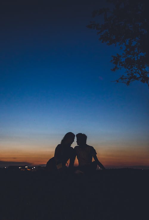 Free Silhouette of Man and Woman Sitting on the Rock Stock Photo