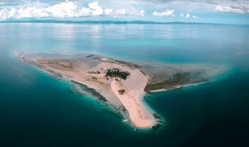 Aerial view of tropical island with trees and sandy beach located in blue ocean