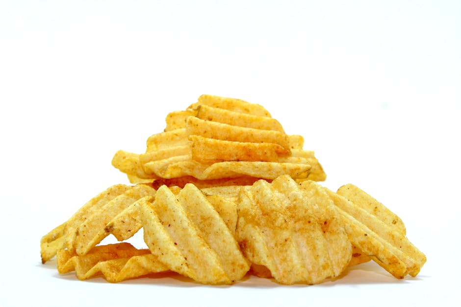 A close-up of crispy wavy potato chips stacked against a white background, highlighting their texture.