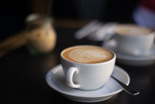 Free Close-up shot of a cappuccino in a ceramic cup on a table with blurred background in Berlin cafe. Stock Photo