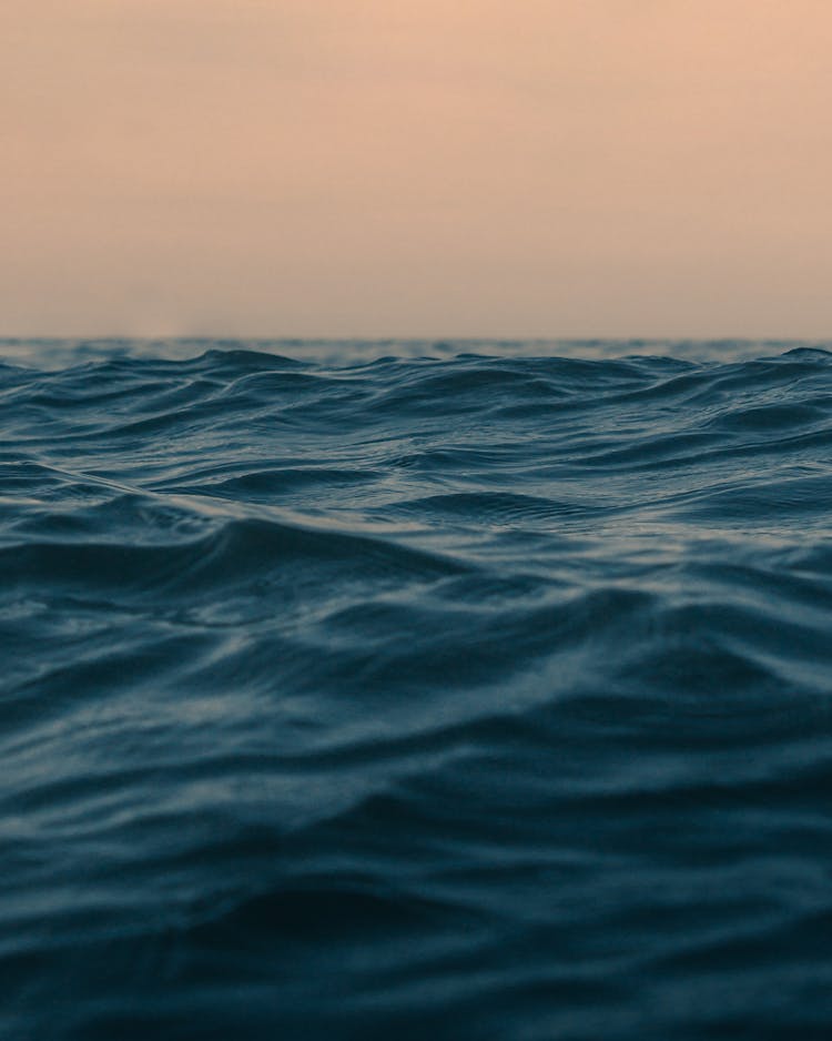 Wavy Ocean With Horizon Under Sky At Sunset