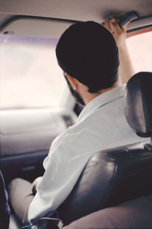 Free Back view of a man in a beanie riding inside a car, holding the handle. Stock Photo