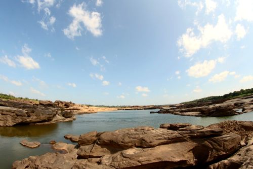 Free A beautiful river scene featuring rocky banks, clear blue sky, and scattered clouds during the day. Stock Photo