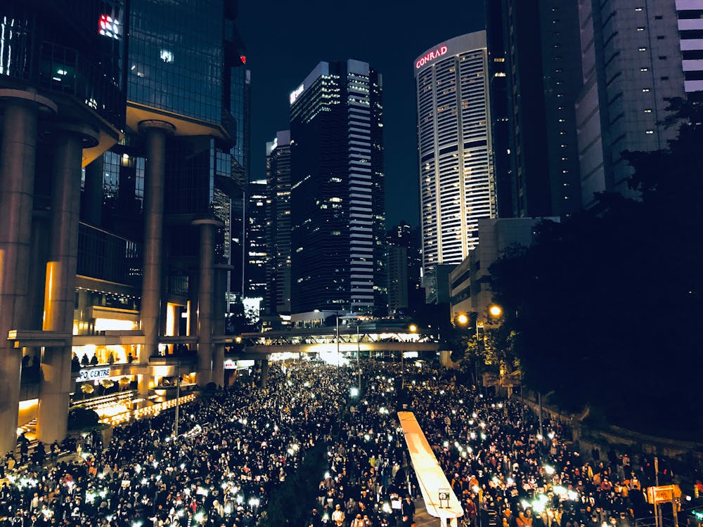 Free From above of crowd of people standing on street in dark modern city centre during mass protest Stock Photo
