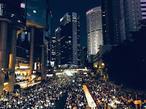 From above of crowd of people standing on street in dark modern city centre during mass protest