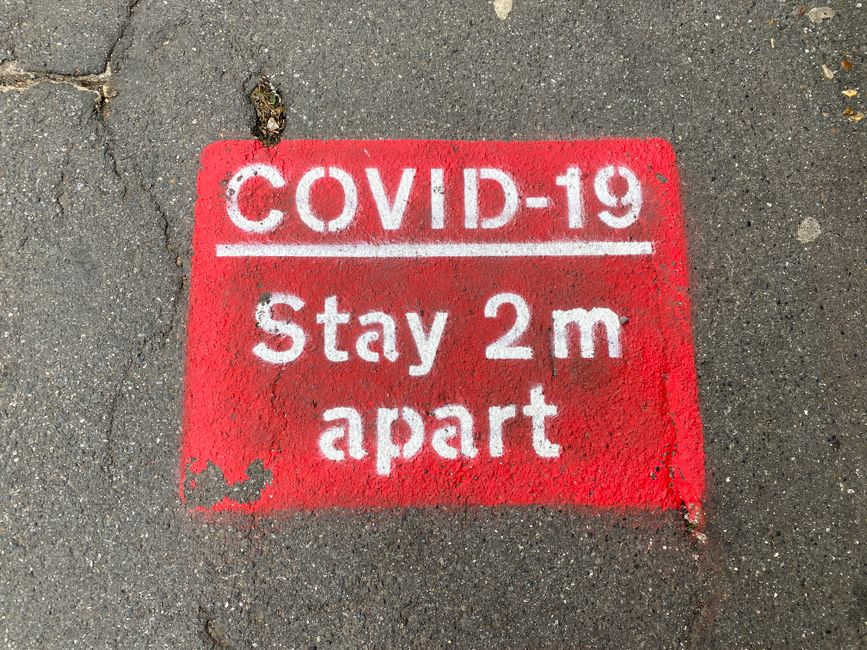 Covid-19の間、2メートルの距離を保つよう人々に促す赤と白の路面標示。