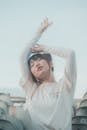 Woman in White Long Sleeve Shirt with Hands Raised