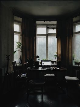Interior of modern light workplace with contemporary netbook placed on table near chairs and windows with green plants in apartment