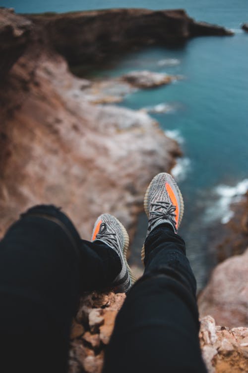 From above of crop unrecognizable traveler contemplating sea from high mountain during trip