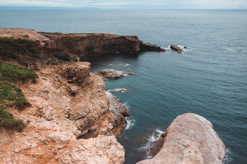 Breathtaking view of blue rippling sea washing rocky rough cliffs on clear summer day