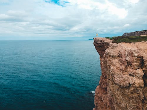 Free Person standing on cliff over ocean Stock Photo