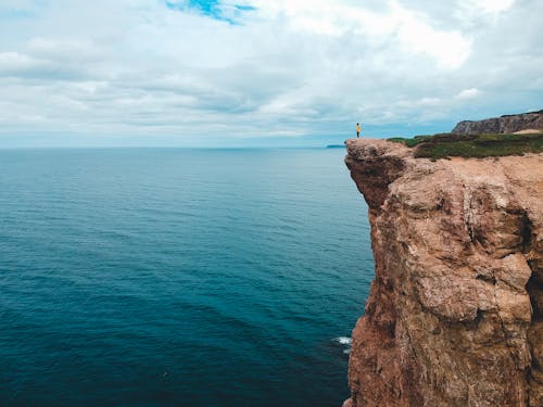 Person standing on cliff over ocean