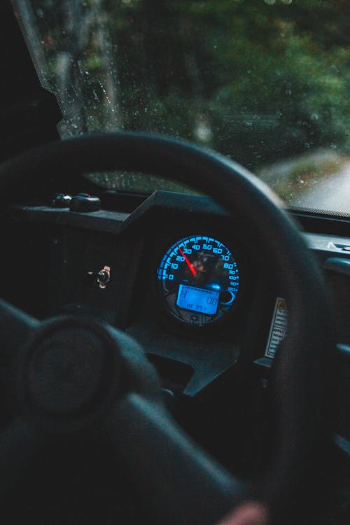 Big black round steering wheel and glowing speedometer in cabin of modern automobile in daylight