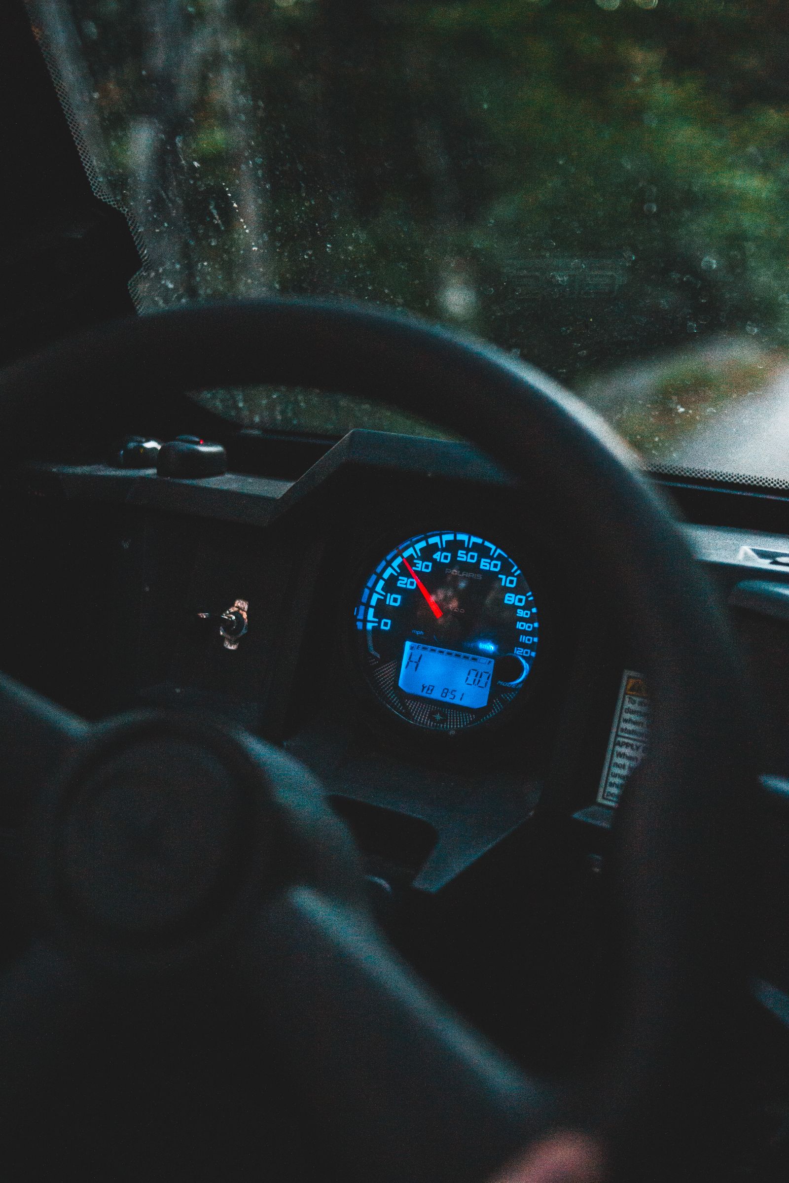 Steering wheel and illuminated speedometer inside a car at night