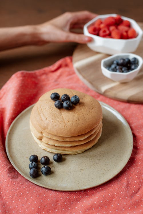 Free Crop woman at table with pile of tasty hotcakes Stock Photo
