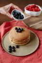Crop woman decorating delicious pancakes with fresh blueberries