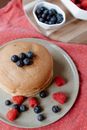 Heap of tasty pancakes with sweet berries on plate