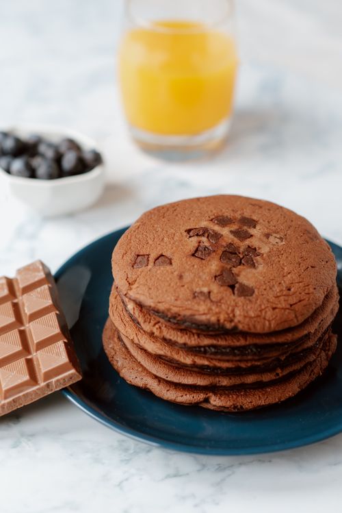 Free From above of portion of delicious brown hotcakes with chocolate chips near glass of orange juice Stock Photo
