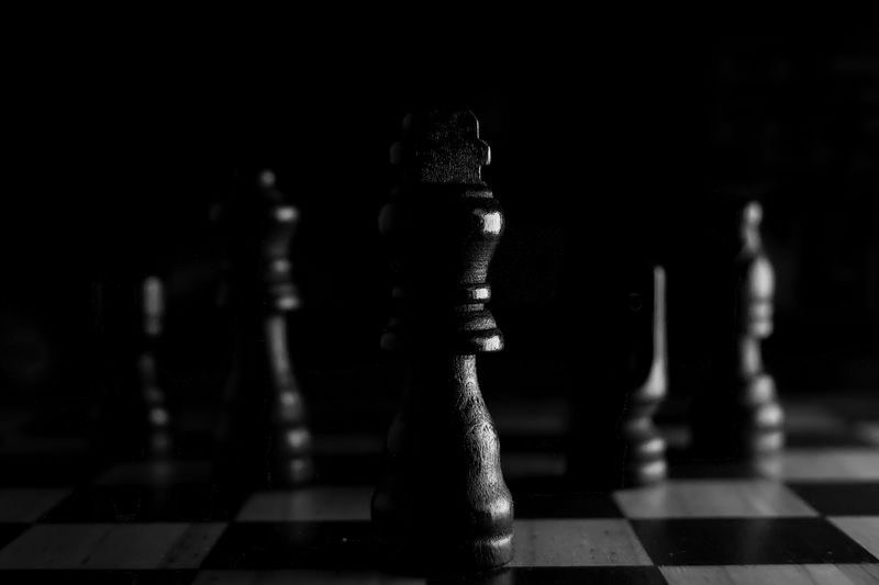 Strategic close-up of chess pieces on a board, highlighting the queen in black and white.