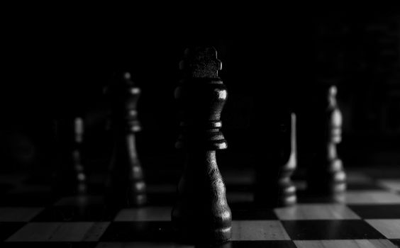 Strategic close-up of chess pieces on a board, highlighting the queen in black and white.
