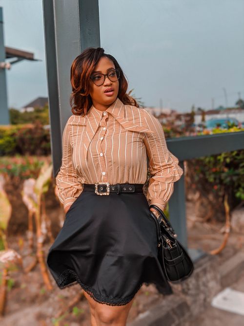 Free Stylish woman in glasses and chic attire poses confidently in an outdoor urban setting. Stock Photo