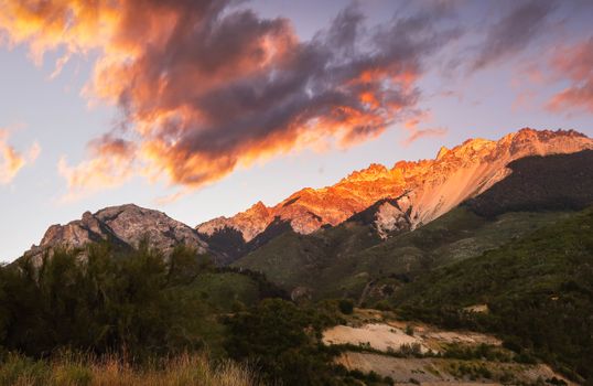Spectacular sunset clouds over a green mountainous landscape, capturing nature's beauty at golden hour.