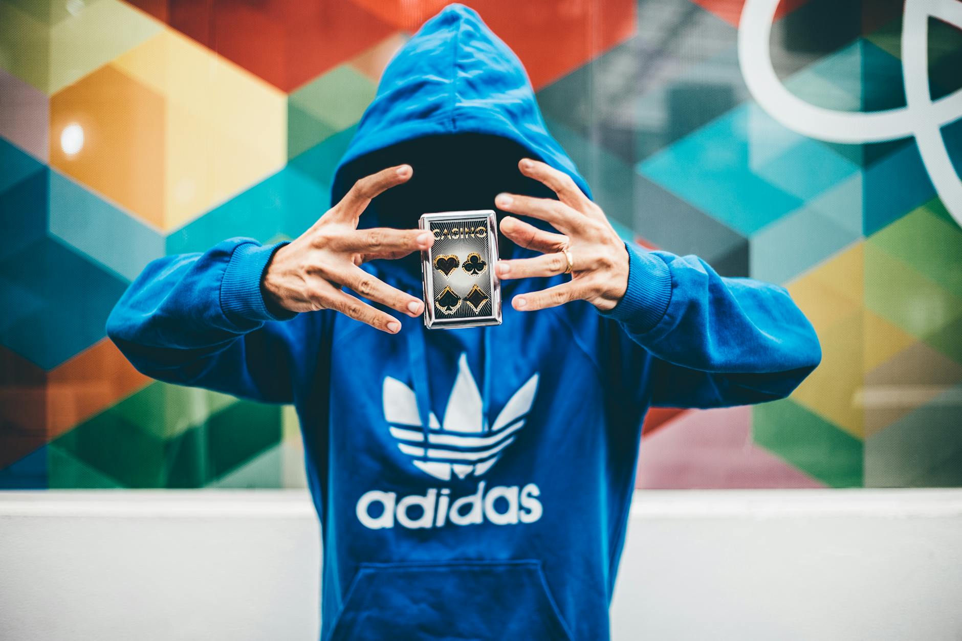 guy wearing a blue adidas hoodie while performing with a deck of cards