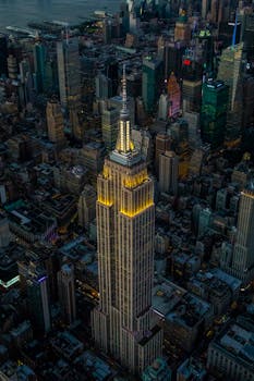 Stunning aerial view of Empire State Building illuminating New York City skyline at night.