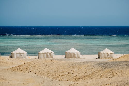 Beach tents placed on sandy seacoast in tropical resort camp