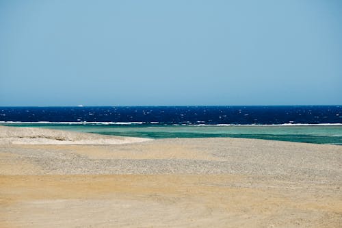 Scenic view of wavy blue sea washing desolated sandy beach on clear summer weather