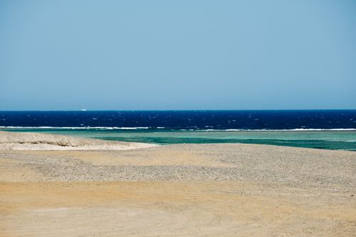 Free Scenic view of wavy blue sea washing desolated sandy beach on clear summer weather Stock Photo