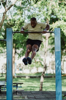 Athletic man doing muscle up exercise on a pull-up bar in a scenic outdoor park.