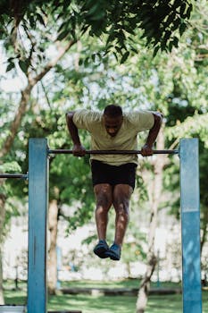 A man exercises on a pull-up bar in an outdoor park setting.