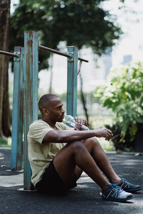 
A Man Drinking Water while Sitting on the Ground