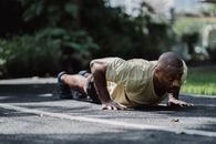 一名成年男子在宁静的公园里专注地做着俯卧撑，锻炼身体
