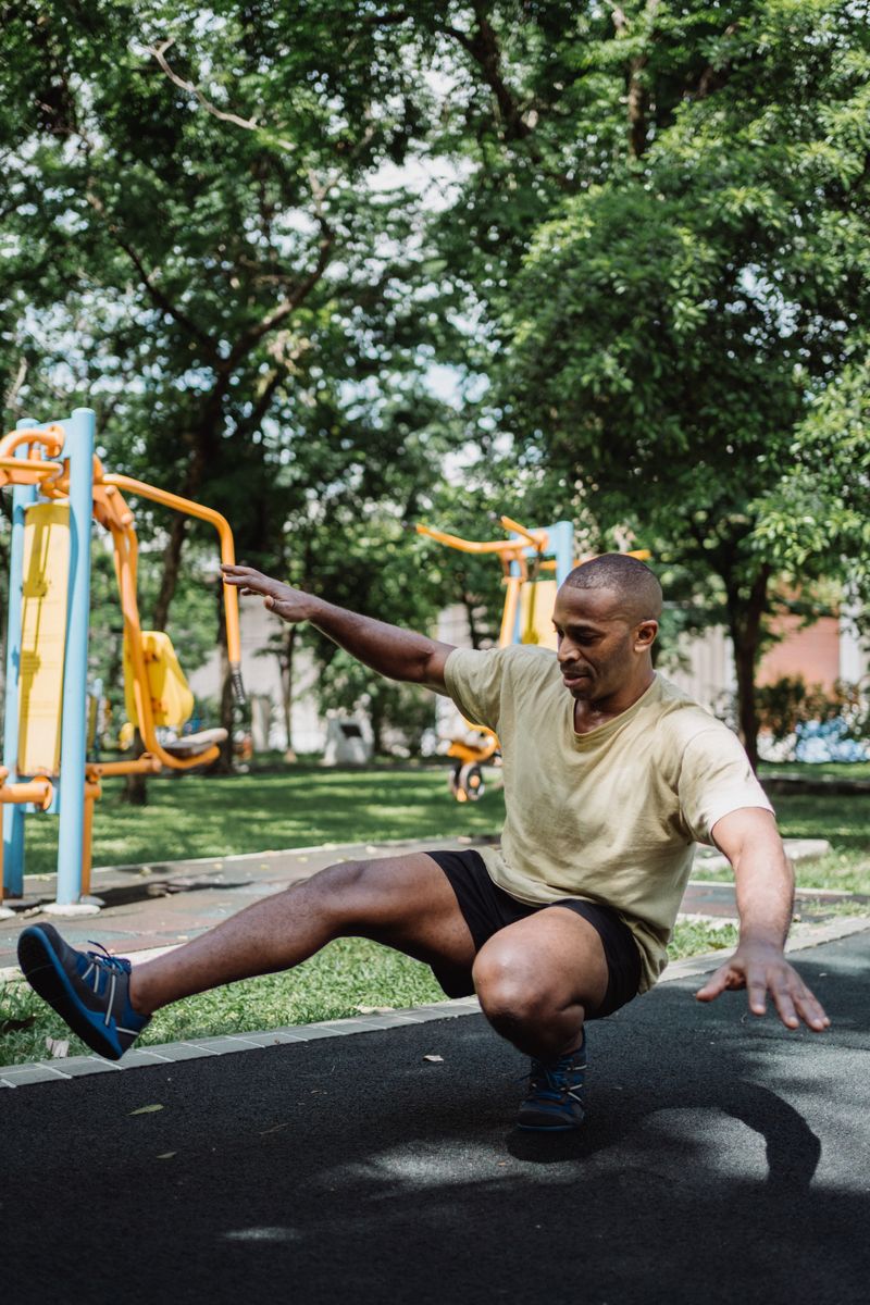 Man doing outdoor squat exercise in a park, showcasing fitness and healthy lifestyle.