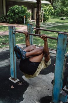 Man doing a fitness exercise on an outdoor dip bar in a park setting, showcasing strength and fitness skills.