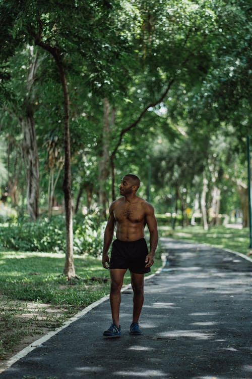 Shirtless Man Wearing Black Shorts Walking on Pathway