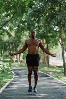 Athletic man exercises with a jump rope outdoors in a green park, promoting a healthy lifestyle.