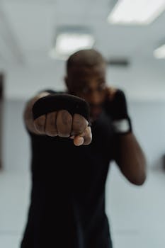 A boxer fully focused on his craft, throwing a powerful punch indoors.