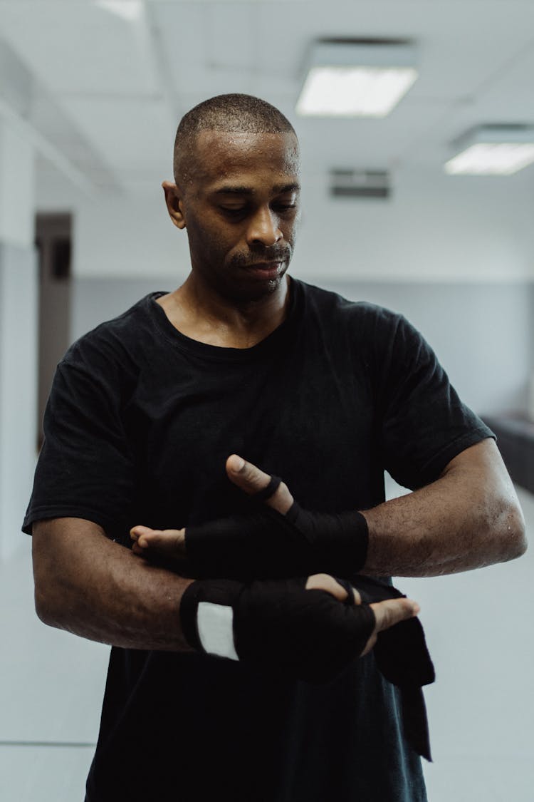 Man In Black Shirt Wrapping His Hand With A Sport Bandage