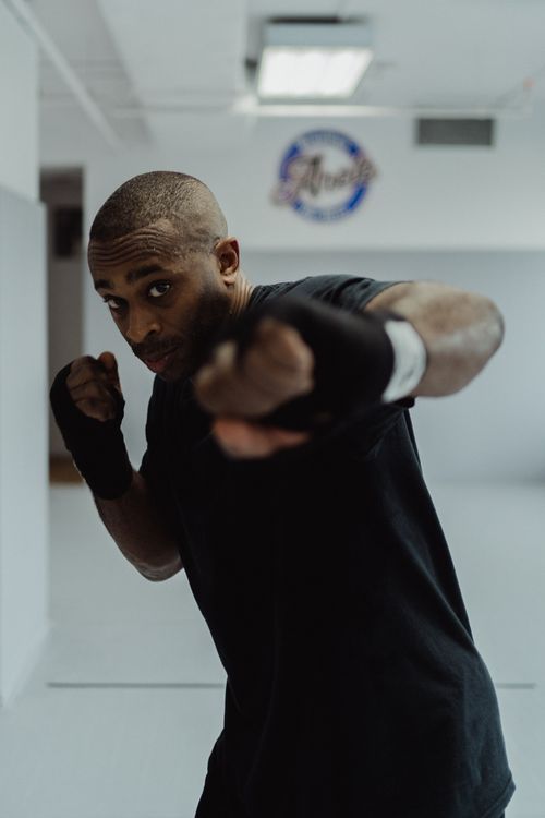 Free African American man practicing shadow boxing in a well-lit indoor space, focused on fitness and self-defense. Stock Photo