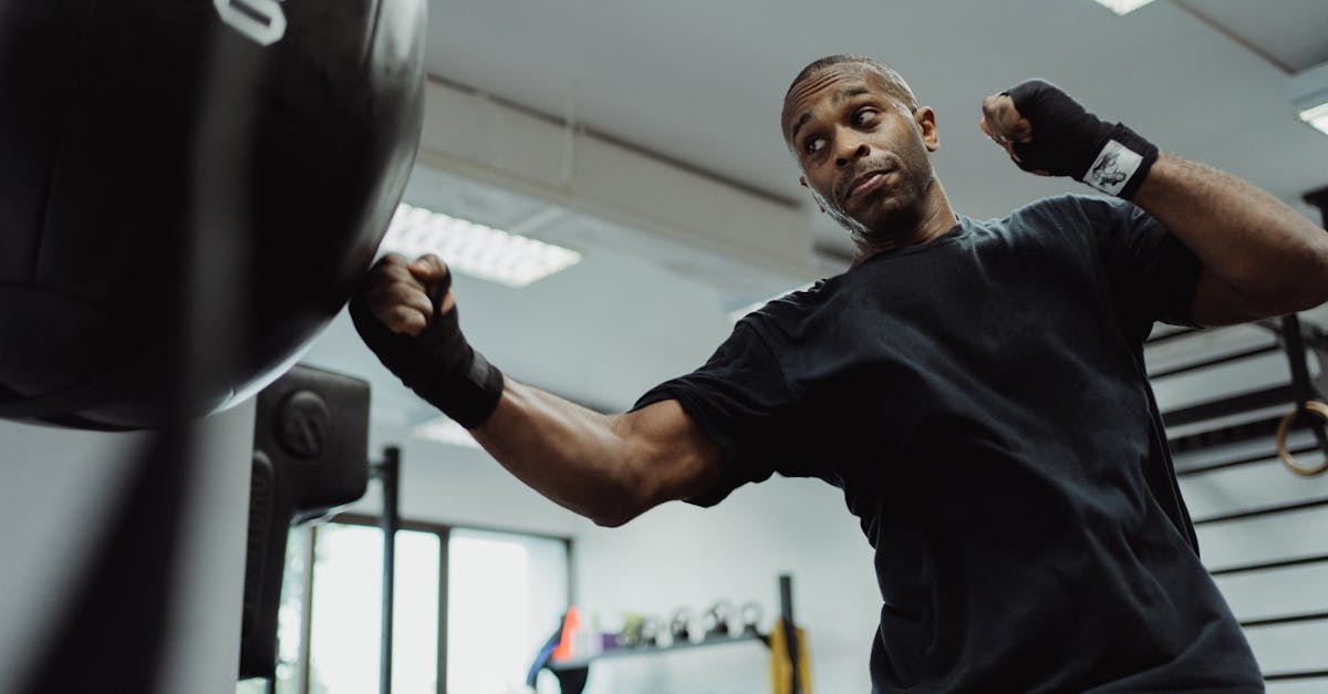 A determined male boxer practices powerful punches on a heavy bag in a modern gym.