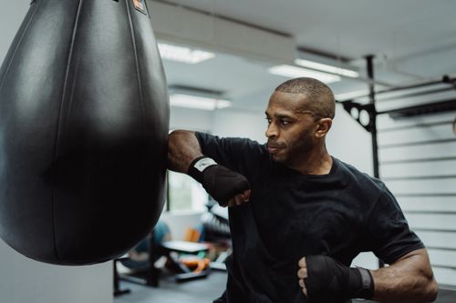 Free A focused boxer practices punches with a punching bag in a gym setting. Stock Photo