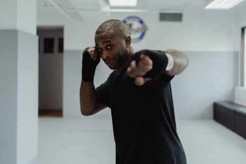 Free African American boxer in a gym, ready with bandages and stance, showcasing determination. Stock Photo