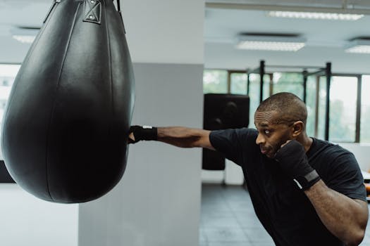 A dedicated athlete practicing boxing techniques indoors with a hanging bag.